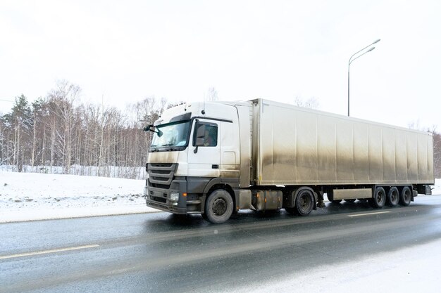 Een oplegger vrachtwagen oplegger trekker eenheid en oplegger om vracht vrachtvervoer te vervoeren in harde winteromstandigheden op glibberige ijzige en besneeuwde wegen