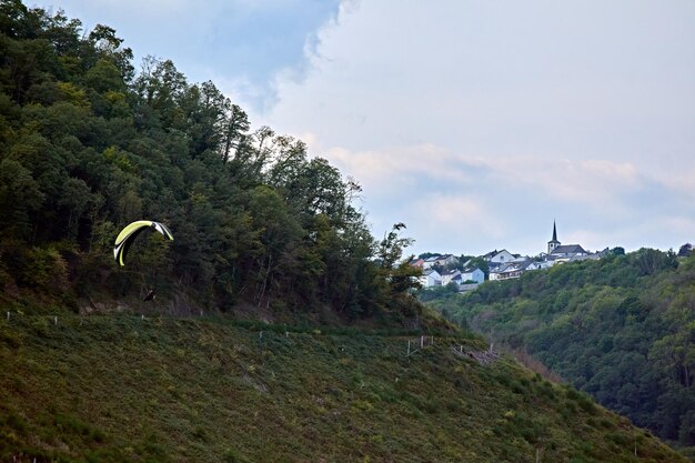 Een opname van een paragliding in een prachtig landschap met het groene bos en een dorp