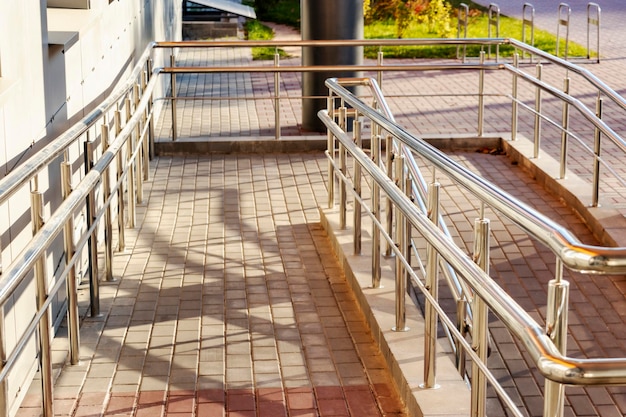 Een oprit en metalen leuningen bij de ingang van het woongebouw voor het gemak van mensen met een handicap en ouderen