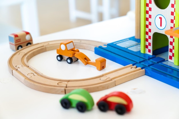 Een oranje houten speelgoedgraafmachine wordt op de tafel geplaatst voor andere wazige houten speeltjes