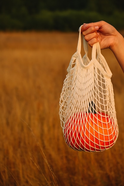 Een oranje pompoen in een natuurlijke katoenen milieuvriendelijke tas in een dameshand