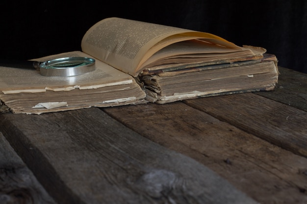 Een oud bruin boek en een vergrootglas op rustieke achtergrond.