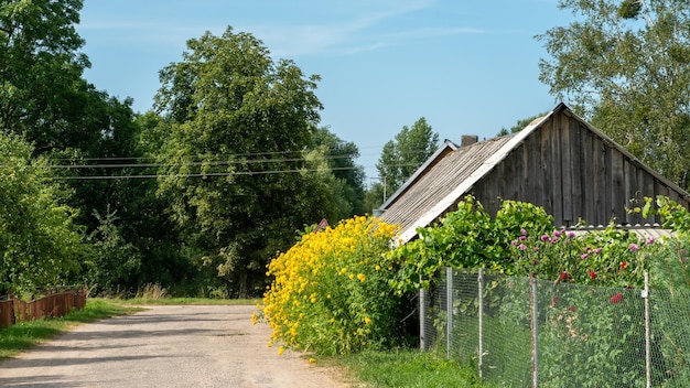 Een oud houten huis in het dorp aan de weg mooie bloemen en een tuin bij een klein dorpshuis het leven in het dorp weg van de drukte van de stad