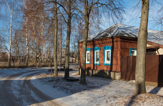 Een oud houten huis met blauwe gebeeldhouwde architraven op een zonnige winterdag