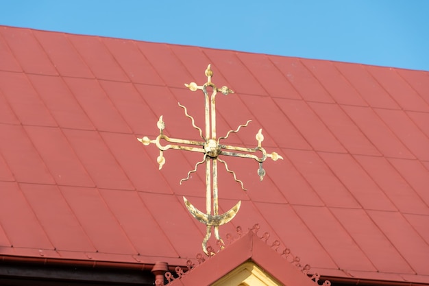 Een oud roestig metalen kruis op een rode achtergrond Het rode dak van een kleine dorpskerk Een christelijk kruis met een wassende maanclose-up