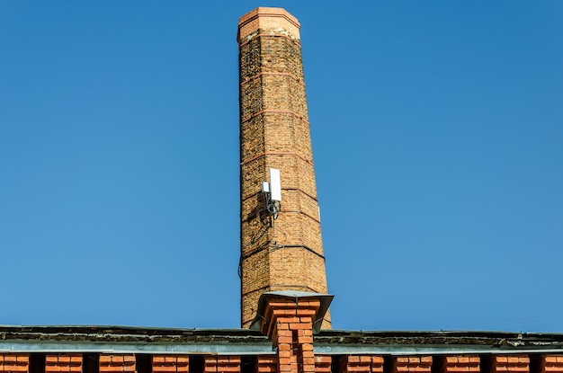 Een oude bakstenen pijp met cellulaire communicatieantennes.