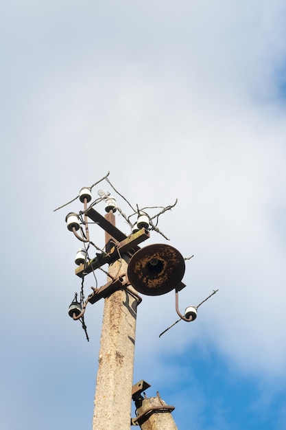 Een oude betonnen straatpaal met een roestig ijzeren deel aan de bovenkant en doorgeknipte draden Installatie of demontage van het elektriciteitsnet Een kapotte energiezuil