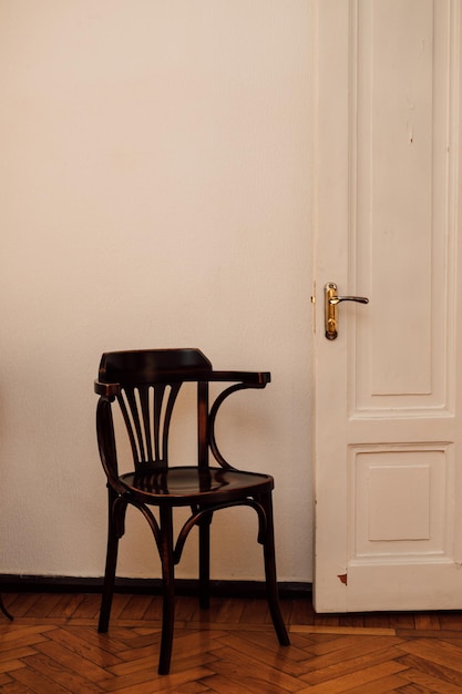 Een oude bruine stoel staat in een kamer bij een open deur