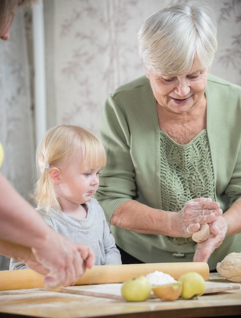 Foto een oude dame die kleine ronde taarten maakt met een klein meisje portret