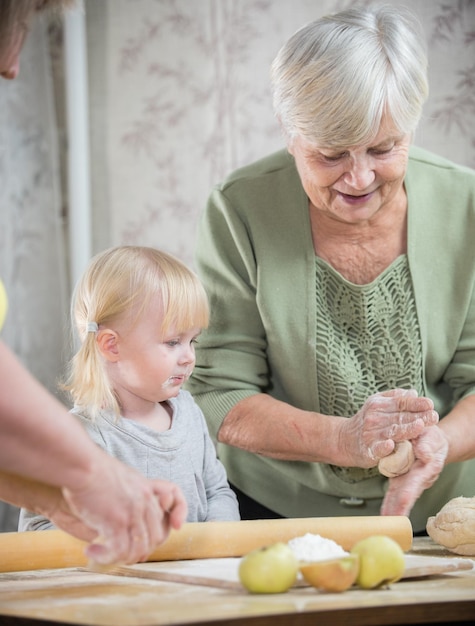 Een oude dame die kleine ronde taarten maakt met een klein meisje Portret