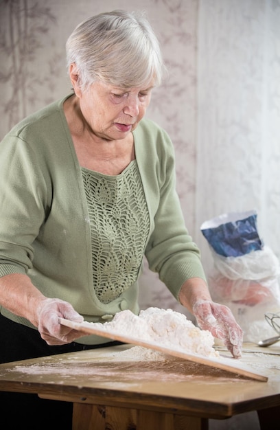 Een oude dame die taartjes maakt Kneed het deeg Portret verticaal shot