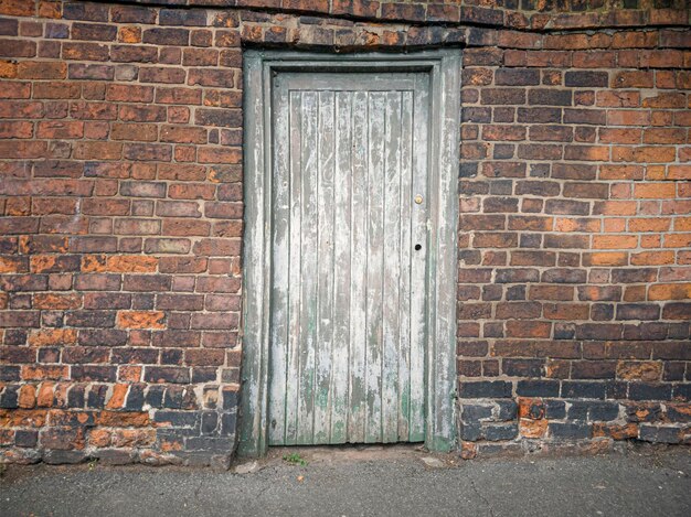 Een oude deur in oude bakstenen muur