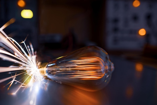 Een oude doorzichtige glazen gloeilamp schijnt niet erg fel met een amberkleurig vurig licht en giet snel en scherp