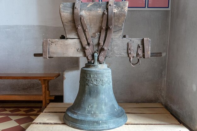 Een oude grote gietijzeren bel ligt op de vloer bij de ingang van de kerk Restauratie van culturele waarden van religieuze betekenis