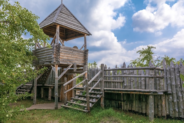 Een oude houten uitkijktoren en een palissade gemaakt van boomstammen Bescherming van een oud Russisch dorp