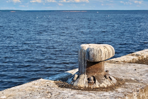 Een oude ijzeren bolder close-up aan de kust op een betonnen plaat om het schip aan te meren