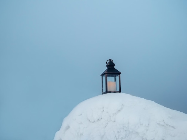 Een oude kaarslantaarn staat op de avondsneeuw in de ijzige winter