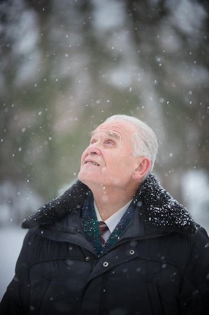 Een oude man die in de winter buiten staat en omhoog kijkt