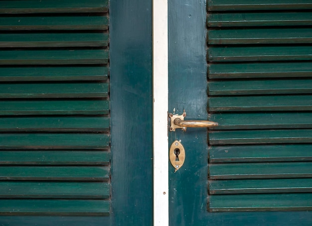 Een oude metalen deurklink op groene vintage houten Javaanse deur