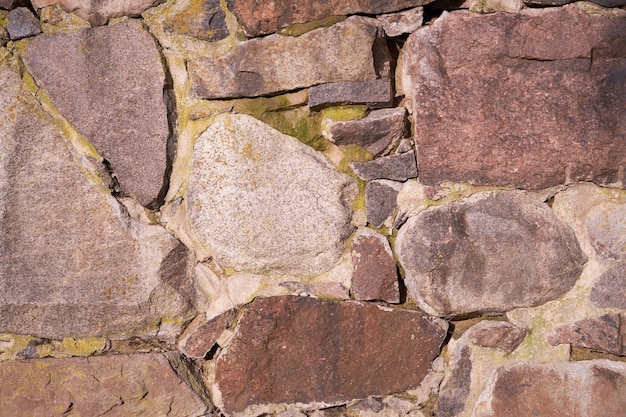 Een oude muur van granieten stenen van verschillende grootte als achtergrond.