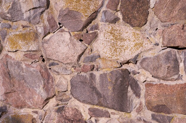 Een oude muur van granieten stenen van verschillende grootte als achtergrond.