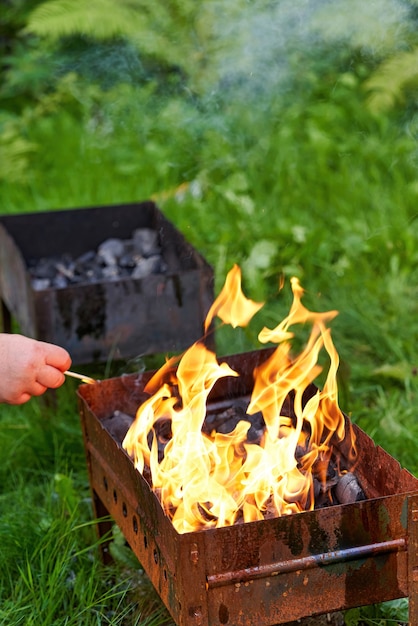 Een oude roestige metalen barbecue aansteken, rook en vuur. Voorbereiden voor een buitenbarbecue