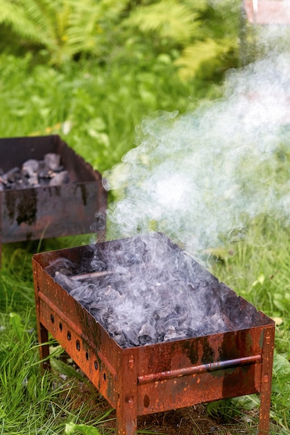 Een oude roestige metalen barbecue grill rook en vuur aansteken