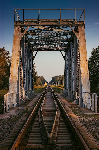 Een oude roestige metalen spoorbrug op een warme zomeravond