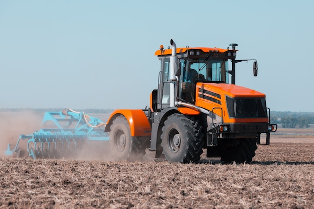 Een oude tractor werkt in het veld. Landbouw werk.