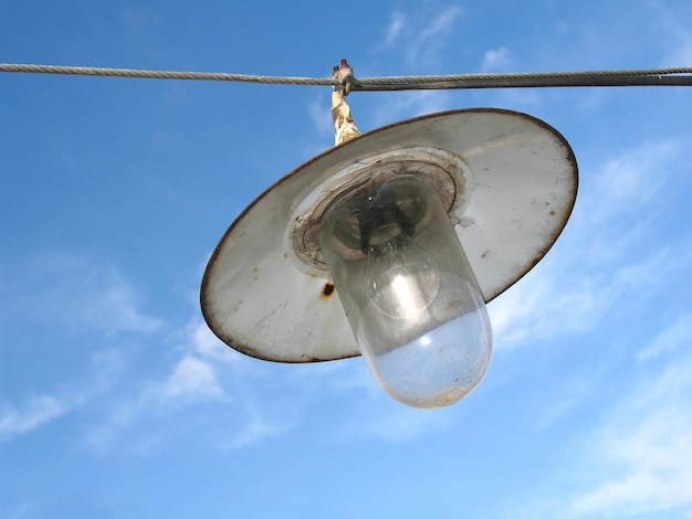 Een oude vintage lantaarn die aan een draad hangt met een hemelachtergrond van een gloeilamp