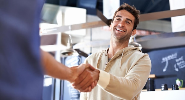 Foto een oude vriend tegen het lijf lopen een jonge man die een vriend de hand schudt in een coffeeshop