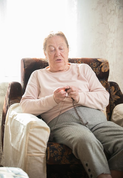 Een oude vrouw die in de fauteuil zit te breien