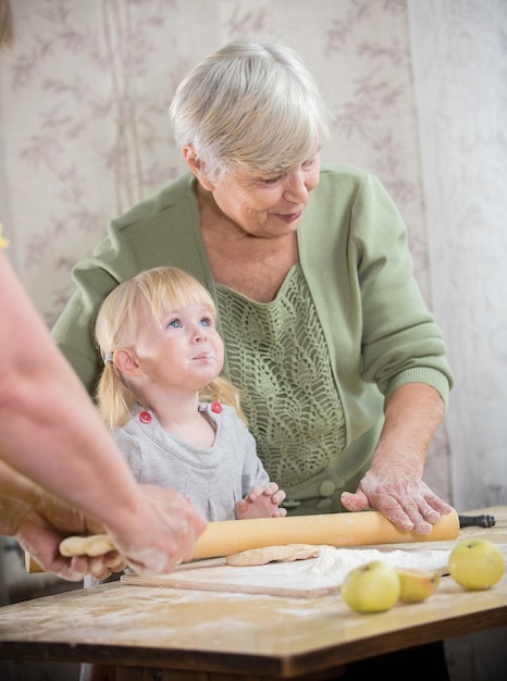 Een oude vrouw die taartjes maakt met haar kleindochter meel op meisjeslippen