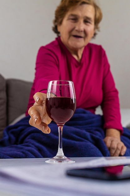 Een oude vrouw drinkt thuis wijn Selectieve aandacht