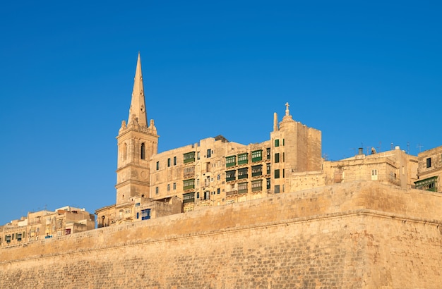 Een oude zandstenen kerk en huizen in Valletta, Malta