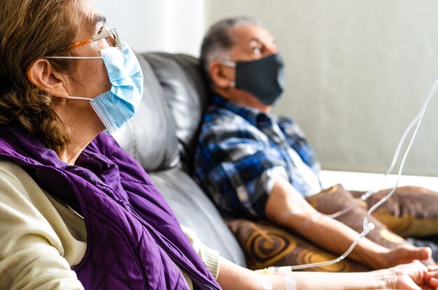 Een ouder echtpaar draagt een masker in het ziekenhuis.