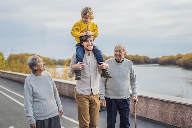 Een ouder echtpaar loopt in het park met een rivier met hun kleinzoon en achterkleinzoon