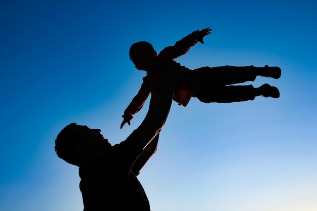 Een ouder met een kind dat op het strandsilhouet speelt