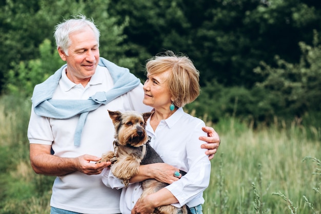 Een ouder stel loopt met een hond in een park