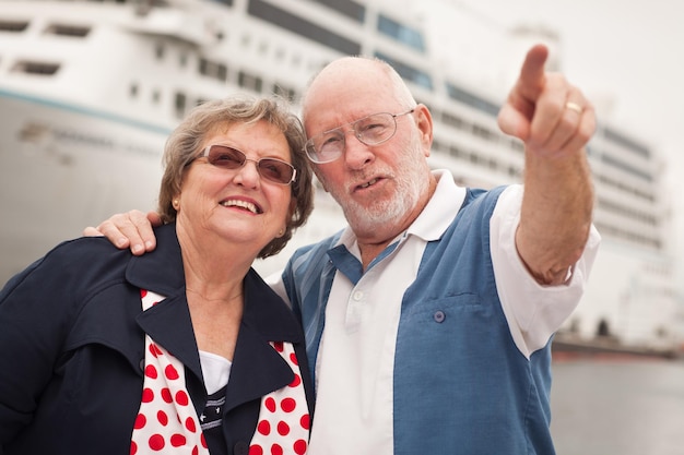 Een oudere echtpaar aan wal voor een cruiseschip