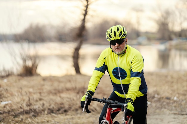 Een oudere fietser fietst langs de rivier in de natuur