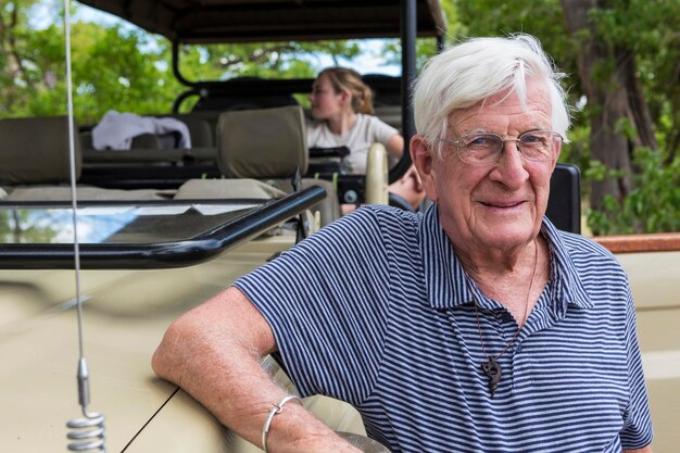 Foto een oudere man die bij een safari-jeep staat te glimlachen