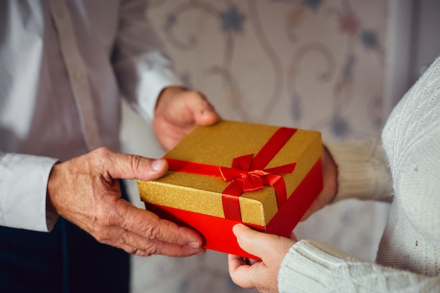 Een oudere man geeft een geschenk aan zijn geliefde vrouw