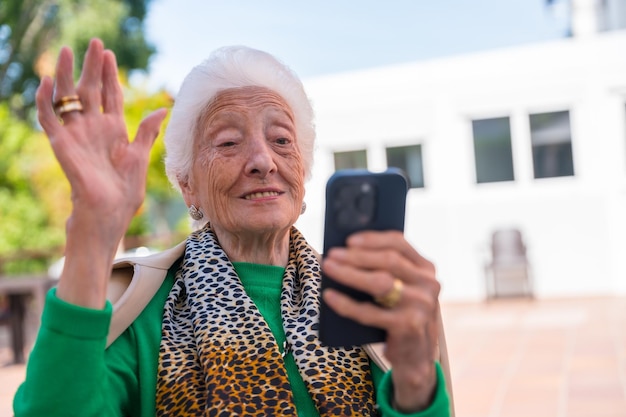 Foto een oudere man in de tuin van een verpleeghuis of bejaardentehuis op een zonnige zomerdag kijkend naar de telefoontechnologieën bij ouderen
