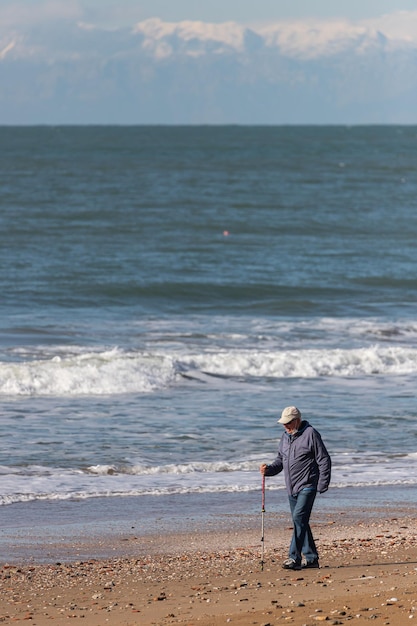 Een oudere man loopt en geniet van de zonsondergang over de zee met een prachtige horizon wonderen van de natuur prachtig landschap van de winterse zee