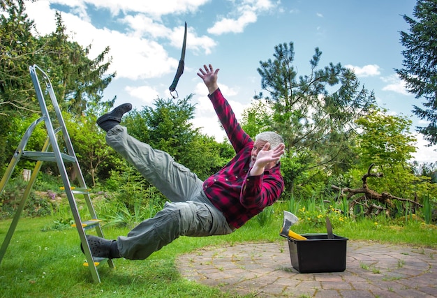 Foto een oudere man valt van een ladder in de tuin.