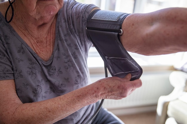 Foto een oudere oudere vrouw controleert haar bloeddruk bij het thuiszorgconcept