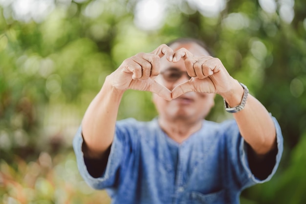 Foto een oudere thaise man maakte met zijn hand een hartvormig symbool door het voor zich uit te steken