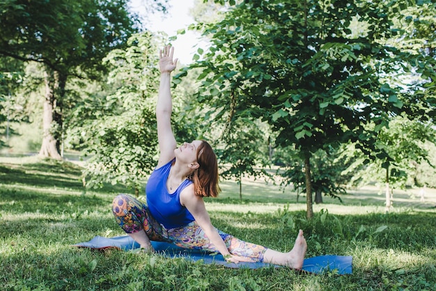 Een oudere vrouw doet yoga in het park op een mat Voert complexe asana-oefeningen uit en leidt een gezond leven