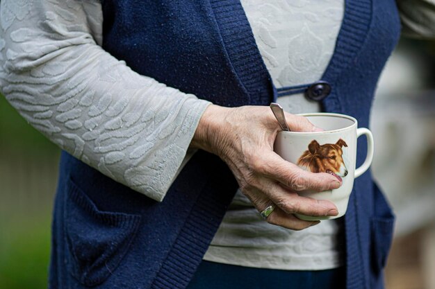 Een oudere vrouw houdt een kopje vast met een afbeelding van een collie-hond